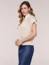 Buzo de punto color marfil, confeccionado en algodón calado con cuello alto acanalado y medio cierre metálico dorado. Presenta mangas cortas estilo japonesa con puños anchos y un zócalo acanalado en el ruedo.