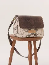 Cartera tipo bandolera con solapa de gamuza color tostado, cuerpo con estampado de piel de serpiente y detalle frontal en cuero texturizado color marrón. Incluye correa ajustable y herrajes metálicos.