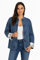 Campera de jean azul con cuello mao y cierre frontal mediante nudos decorativos. Presenta mangas largas con puños vueltos en color blanco con bordados florales y bolsillos frontales tipo parche.