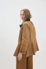 Chaqueta de lino marrón con cuello mao en contraste negro, cierre frontal con botones y hombreras.