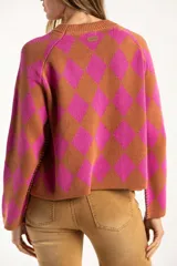Sweater de punto con diseño de rombos en colores fucsia y tostado, cuello redondo y mangas largas.