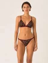 Conjunto de lencería compuesto por un corpiño triangular y una bombacha tipo vedetina, ambos con estampado animal print y bordes en color bordó.