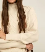 Suéter de manga larga confeccionado en tricot, con cuello alto y diseño de rombos bordados en relieve. Presenta puños y cintura ajustados en tejido acanalado.