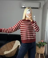 Sweater de punto con diseño de rayas horizontales negras sobre fondo blanco, cuello redondo y puños y ruedo acanalados.