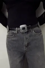 Cinturón negro de símil cuero con diseño western, apliques metálicos circulares y hebilla cuadrada grabada.