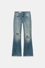 Jeans de tiro medio con diseño flare, efecto lavado y detalles de roturas en las piernas. Presenta cinco bolsillos, trabillas para cinturón y bajo deshilachado sin costuras.