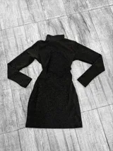 Vestido corto negro con lurex dorado, de cuello alto y mangas largas.