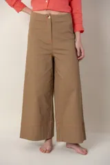 Pantalón ancho color marrón, de tiro alto, con detalle de costuras bordadas en color naranja en ruedo y cintura.