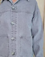 Sobrecamisa de denim con diseño de rayas verticales en tonos azules. Presenta cuello clásico, cierre frontal con botones y bolsillos delanteros de parche.