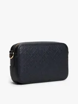 Cartera tipo bandolera Tommy Hilfiger con acabado granulado y diseño integral de monograma TH en relieve. Cuenta con cierre de cremallera, bolsillo exterior frontal con cierre, correa extraíble y apliques metálicos dorados, incluyendo la insignia del monograma TH en el frente.