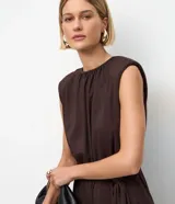 Mono largo color marrón oscuro, sin mangas, con hombreras, escote redondo y lazo ajustable en la cintura. Confeccionado en microfibra.