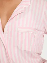 Pijama largo de modal suave con diseño de rayas verticales en tonos rosado y blanco, compuesto por una camisa de manga larga con botones al frente y bolsillo en el pecho, y un pantalón con cintura elástica y cordón ajustable.
