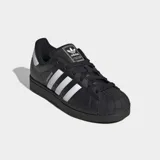 Championes Adidas Superstar II de diseño clásico, color negro con las icónicas tres bandas laterales en blanco. Presentan puntera de goma reforzada, suela de goma al tono y detalle de logo en el talón.