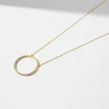 Collar de cadena fina con dije circular de diseño minimalista, elaborado en plata 925 con baño de oro y detalles de circonias engastadas en parte del contorno.