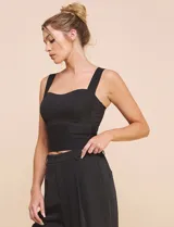 Top crop negro de corte ajustado y estructurado, con escote corazón, tirantes anchos y textura acanalada fina con costuras estilo corsé.