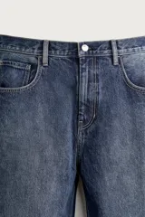 Jeans tapered wide fit de hombre, confeccionados en denim de algodón con efecto lavado en tono azul oscuro. Presentan diseño de cinco bolsillos, tiro medio, corte relajado y cierre frontal con cremallera y botón.