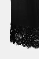 Camiseta de algodón compacto con cuello redondo y manga corta. Presenta un diseño de bajo asimétrico con aplicación de encaje a tono.