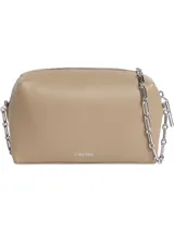 Cartera bandolera Calvin Klein modelo Camera, color beige, confeccionada en poliuretano con cierre de cremallera y correa de cadena plateada. Presenta el logo de la marca en el frente.