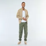 Pantalón cargo de hombre color verde militar, con múltiples bolsillos laterales y puños ajustados elásticos en los tobillos. Presenta cintura elástica con cordón de ajuste.