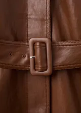 Chaqueta larga de efecto cuero color marrón, con cuello camisero, botonadura frontal oculta, bolsillos laterales y cinturón ajustable con hebilla en la cintura. Cuenta con trabillas en las muñecas y diseño amplio.