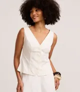 Chaleco femenino color blanco, sin mangas, con escote en V y abotonadura frontal. Presenta pences para un calce entallado y espalda descotada.