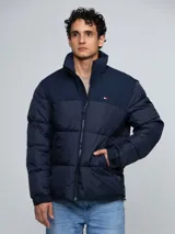 Campera puffer azul marino de cuello alto, acolchada y con cierre frontal de cremallera. Presenta bolsillos laterales con ojal y el logo bordado de la marca en el pecho.