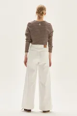 Jean de mujer color blanco, tiro alto, con pierna ancha y corte acampanado. Presenta costuras verticales marcadas en el frente de las piernas.