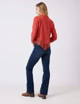 Camisa de algodón con bordado suizo, cuello con solapa y cierre frontal con botones. Presenta mangas largas con terminación de encaje calado y un ruedo asimétrico en pico con un amplio galón de encaje.