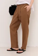 Pantalon de lino color verde militar, de corte recto y holgado, con cintura elastizada y cordón ajustable.
