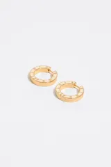 Aros tipo argolla metálicos en tono dorado con esmalte negro y letras grabadas en relieve con el nombre de la marca.