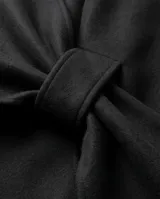 Capa negra de diseño envolvente con un nudo frontal decorativo, confeccionada en tejido suave con caída fluida.