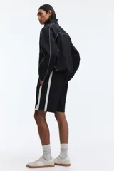Short deportivo negro con bandas laterales blancas, cintura elástica con cordón ajustable blanco y bolsillos laterales.