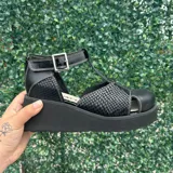Sandalias de plataforma negra con diseño en T, detalles texturizados tipo animal print de serpiente y costuras blancas contrastantes. Cuenta con tira al tobillo con hebilla metálica y cierre trasero.