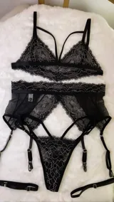 Conjunto de lencería compuesto por un bralette de encaje con tiras decorativas y una bombacha tipo portaligas con detalles en encaje y microtul.