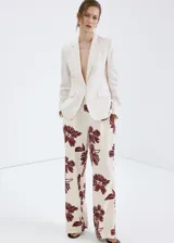 Pantalón de corte regular y tiro medio, con diseño fluido y estampado floral en color bordó sobre fondo beige.