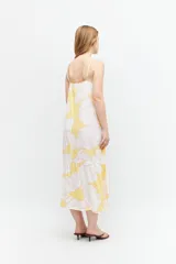 Maxi vestido amarillo con estampado floral blanco y rosa, de tirantes finos y corte holgado.