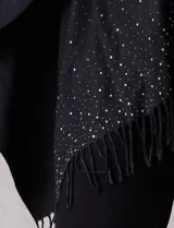 Ruana negra de tejido soft, con detalles de brillos y perlas en los extremos, y terminación con flecos.