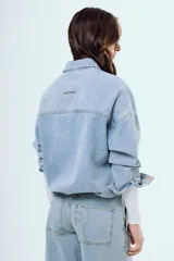 Camisa de denim de corte oversize, color celeste, con bolsillos frontales con solapa y botones metálicos.