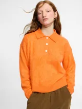 Sweater de punto color naranja con cuello polo y cierre frontal de tres botones. Posee manga larga, hombros caídos y una textura suave tipo pelo, confeccionado en 100% cachemira.