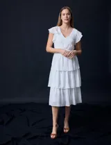 Vestido blanco de gasa con capas, marca Julia Jordan. Escote en V, manga corta con volados, corte en cintura y abertura central en espalda con cierre invisible.