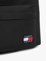 Mochila compacta Tommy Jeans color negro, con diseño curvo, compartimento principal con cierre de cremallera, bolsillo exterior con cremallera y parche con el logo de la marca en la parte delantera. Cuenta con correas ajustables y acolchadas.