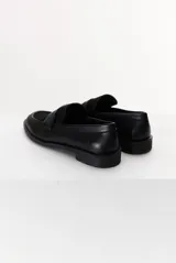 Mocasín color marrón claro, con capellada de cuero liso y aplique de gamuza en marrón oscuro. Tiene punta redondeada y suela plana de goma negra.