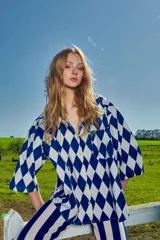 Camisa de corte holgado con estampado de rombos en azul y blanco, cuello solapa, cierre frontal con botones y bolsillo en el pecho.