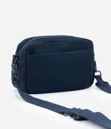 Cartera bandolera de tamaño pequeño, confeccionada en poliéster con estructura ligeramente acolchada. Cuenta con un bolsillo delantero con cierre, compartimento principal con cierre doble y correa ajustable.