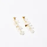 Aros colgantes con base dorada en forma de corazón y colgantes de pétalos blancos.