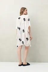 Poncho de gasa liviana color negro, con mangas amplias estilo kimono y bordados florales blancos. Presenta borlas decorativas en los bordes.