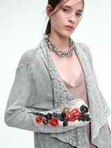 Saco tipo cárdigan largo de tejido térmico con efecto lavado, diseño de solapas amplias con detalle de encaje y mangas decoradas con bordados florales coloridos.