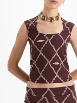 Musculosa de punto color marrón con estampado de cadenas y labios en forma de rombos. Presenta escote cuadrado y corte ajustado al cuerpo.