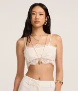 Blusa cropped de encaje color blanco, con escote recto, breteles finos y forro.