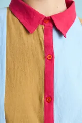 Túnica de algodón con diseño de rayas verticales multicolor en tonos celeste, marrón y fucsia. Presenta cuello polo, manga corta y cierre frontal con botones.